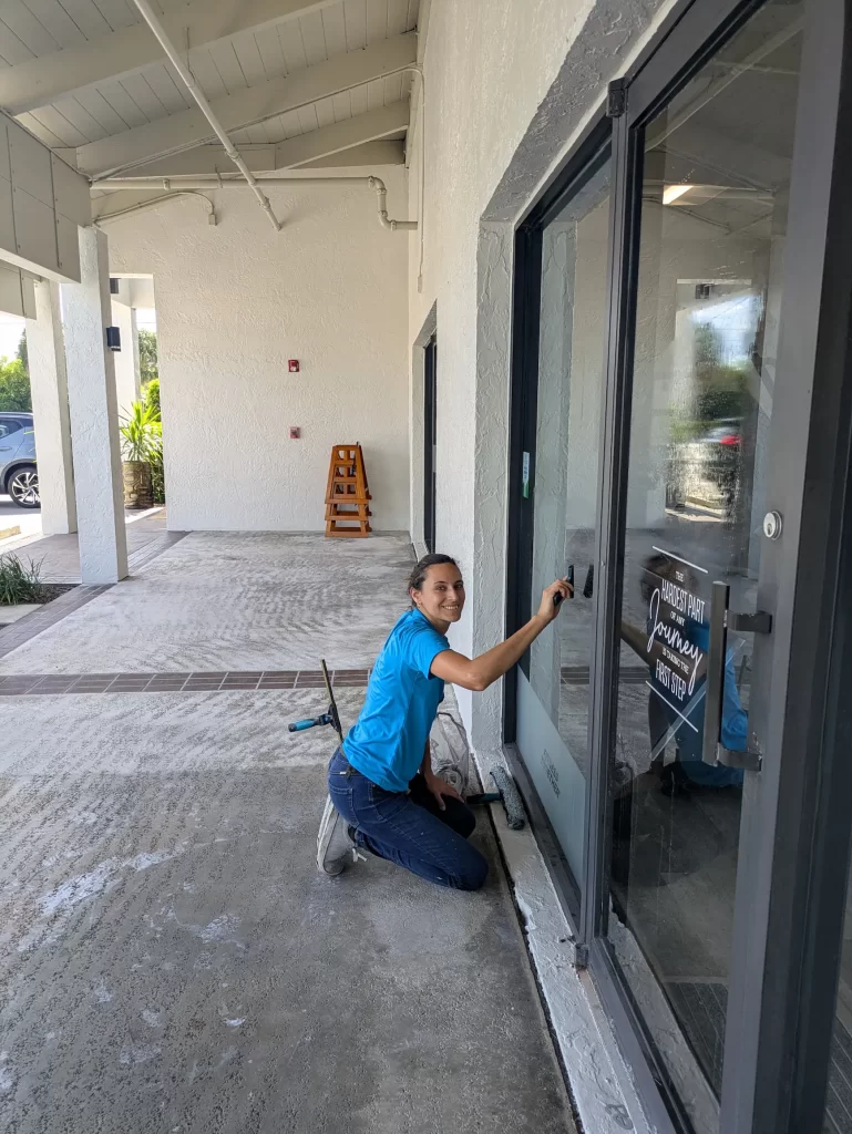 Woman window cleaning storefront in North Palm Beach