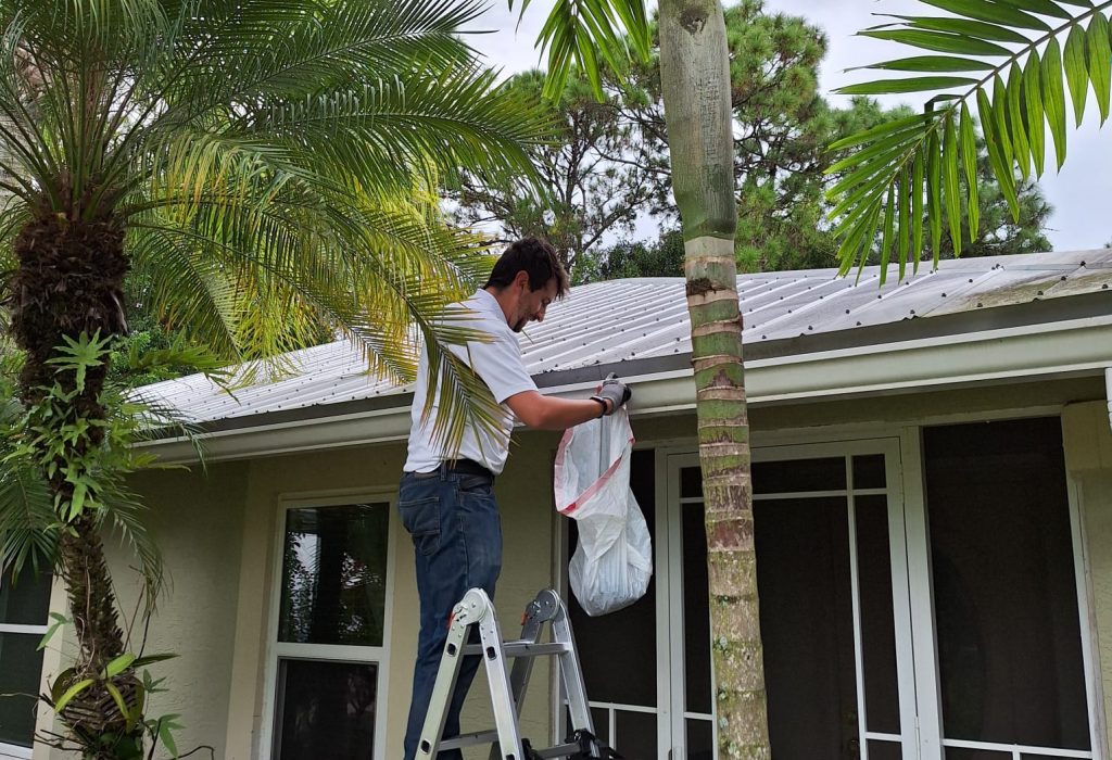 Man cleaning gutters of leaves and pine needles in Jupiter FL